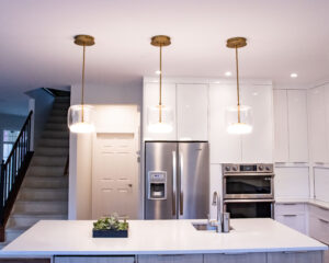 Kitchen layout - set of three pendants over island lighting. Gold inner with cylindrical glass casing