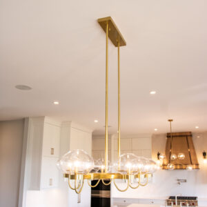 Villosa Ridge After - Brass light fixture with globe lights in front of custom bronze hood fan with two tones of bronze.