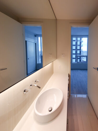 Bathroom vanity with backlit mirror and wall-mounted faucets.