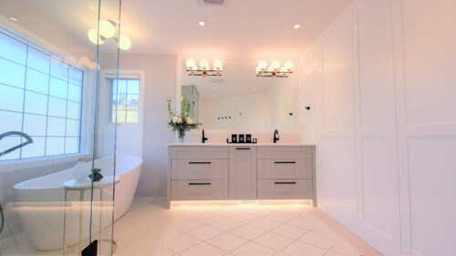 Bright ensuite bathroom with grey double vanity, standalone tub and steam shower. Hidden behind panels is extra storage for all of your hair products.