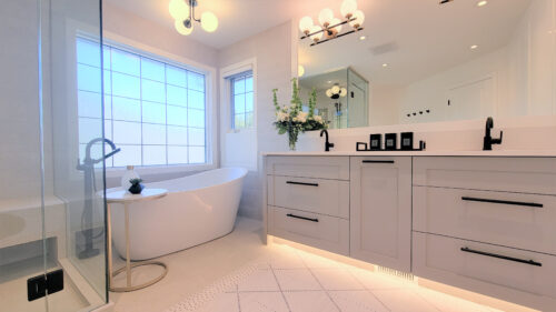 Ensuite bathroom with a standalone tub with a lovely raised end for reading a good book in the bath and a blue-grey vanity and full width frameless mirror.