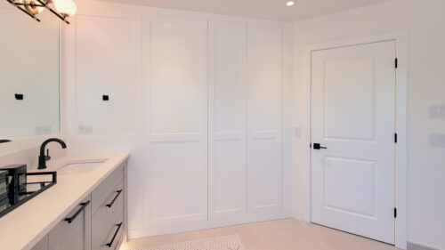 This ensuite bathroom has a hidden cabinet in the wall that looks like beautiful detailed paneling. It's perfect to hold all of your beauty products.