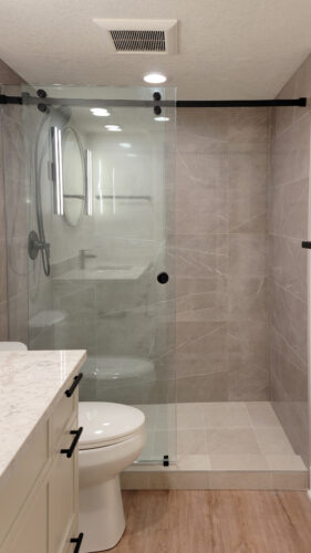 Lower level shared bathroom with exquisite grey marble look tiles in an oversized shower.
