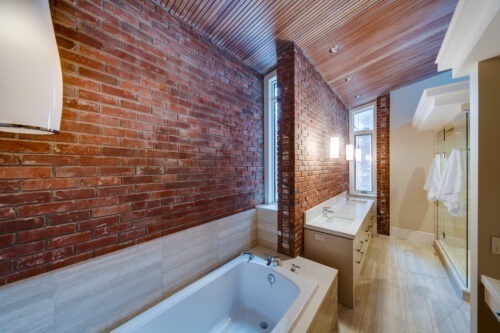 Midcentury modern bathroom ensuite with red brick walls, a double vanity, and a large shower.
