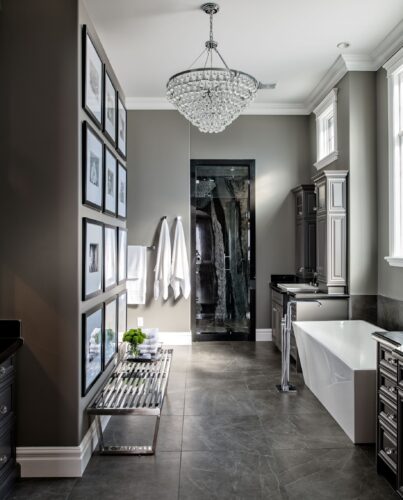Moody dark grey and white bathroom with luxurious chandelier. A rectangular stunning standalone tub and an incredible dark stone double shower.