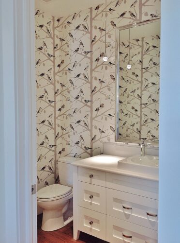 Powder room bathroom with fun bird wallpaper and a white vanity.