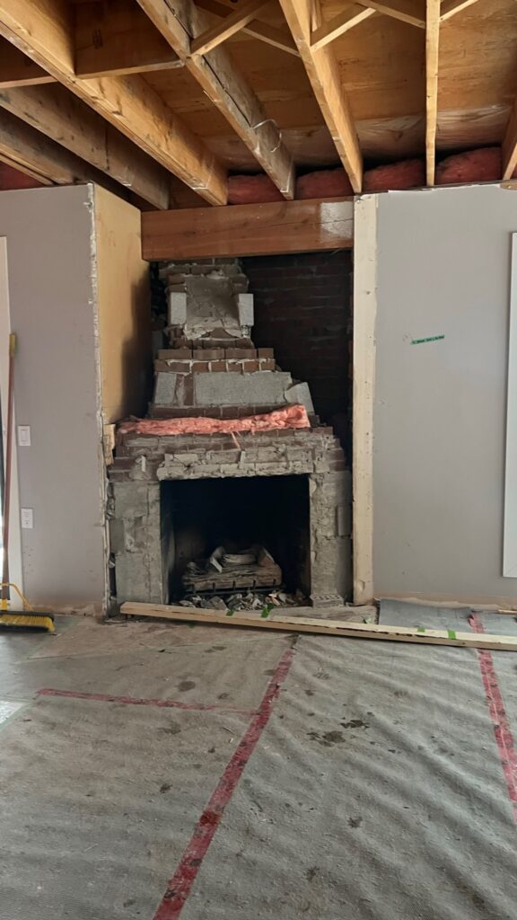 Demolition photo of fireplace reveals poor state of construction on the fireplace that needs to be fixed.