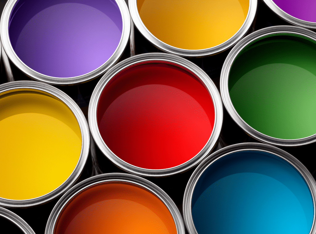 The top view of a bunch of open paint cans in multiple colours with red at the centre and green, blue, yellow, orange and purple surrounding it.