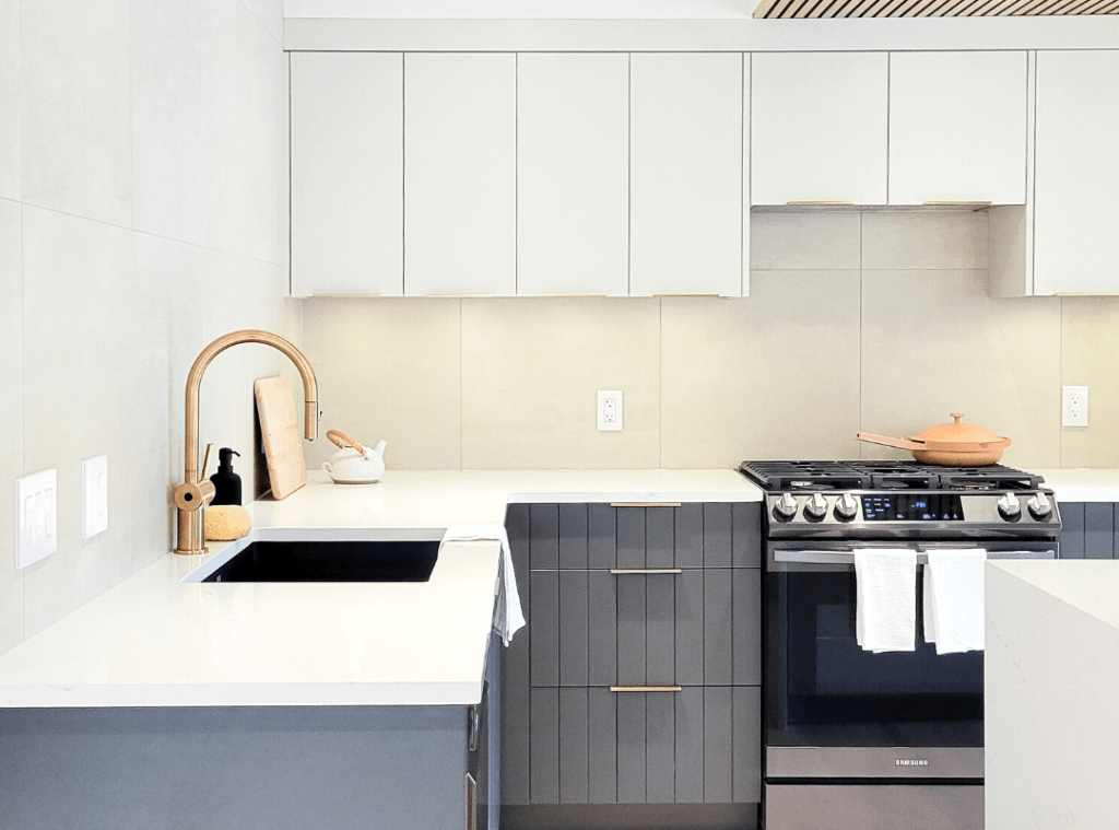 Flat slab light grey upper cabinets and blue lower cabinets. Light large format tiles form a dramatic backsplash.